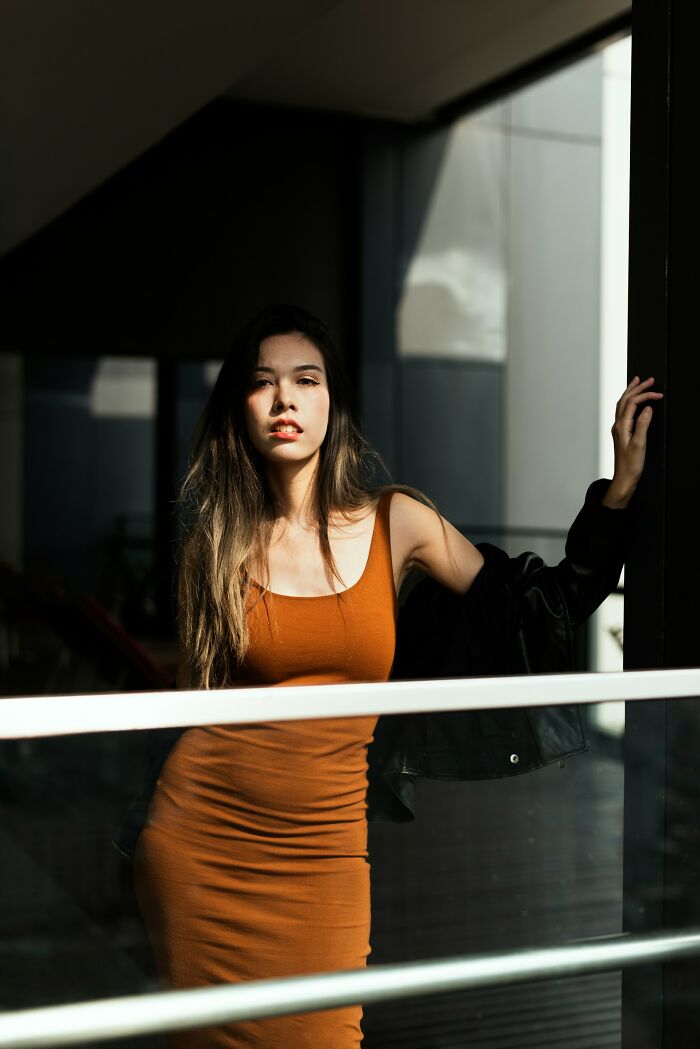 Young woman in a brown dress posing thoughtfully by a window, reflecting on times people drove away potential life partners.