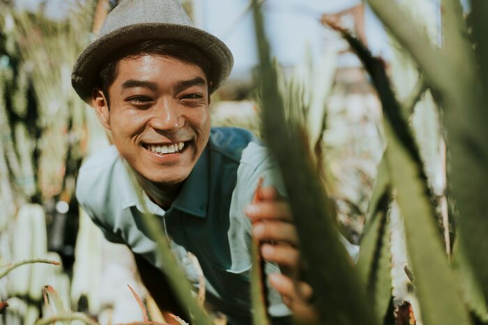 Young man smiling in a hat among plants, illustrating foreigners sharing shortcomings of being big in Japan.