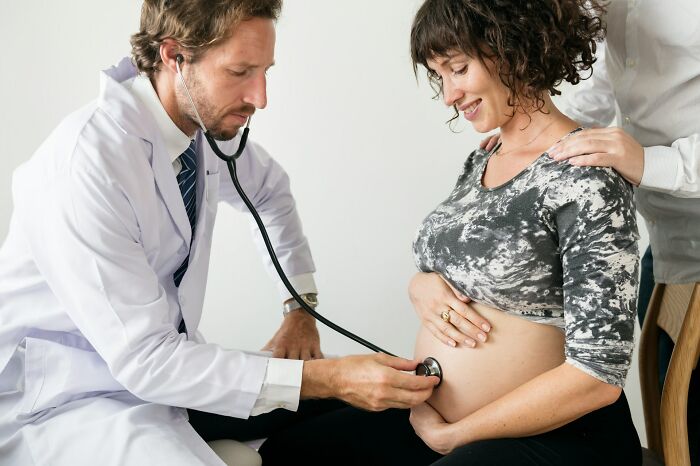 Pregnant woman having prenatal checkup with doctor using stethoscope, illustrating pregnancy childbirth postpartum facts.