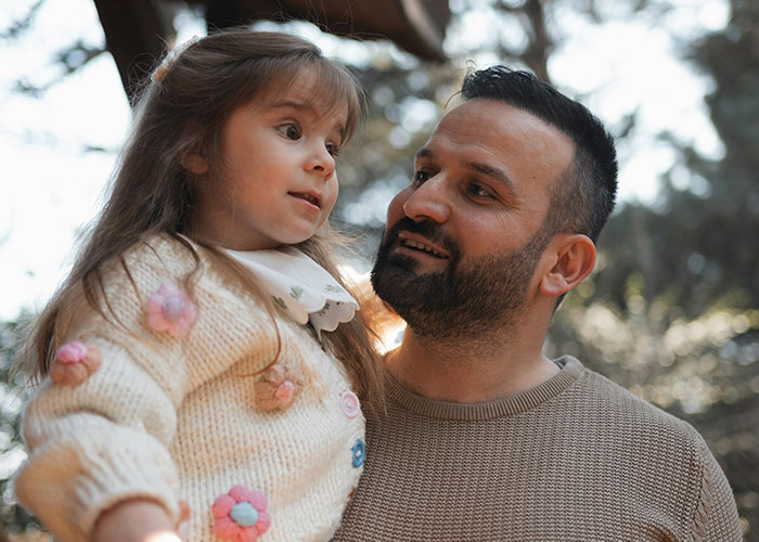 Father holding his daughter outdoors, reflecting on emotional experiences of parents discovering children are not biologically theirs.