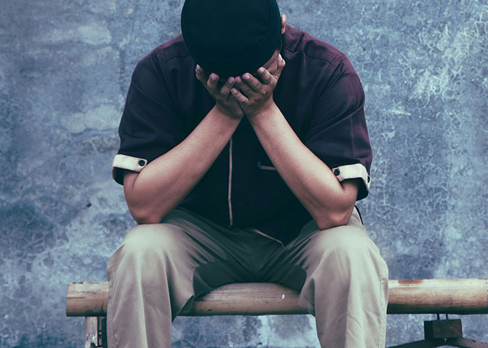 Man sitting on a bench with head in hands, showing emotional pain after finding out kids weren’t biologically theirs.