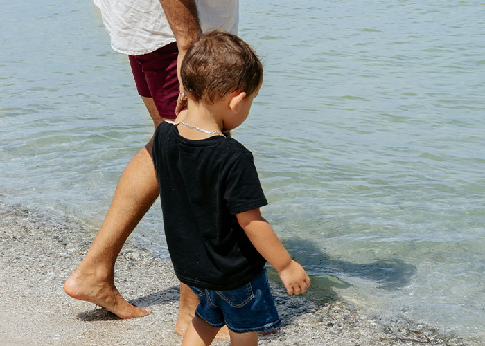 Child and parent walking barefoot by water, representing parents discovering kids aren't biologically theirs.