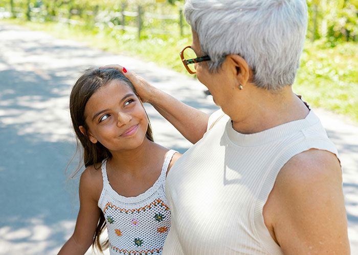Older woman gently touching a young girl’s head, representing parents discovering kids aren’t biologically theirs.