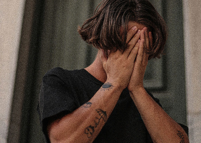 Man covering his face in distress, representing parents' emotional reaction upon finding out kids aren’t biologically theirs.