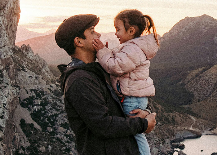 Parent holding child in mountainous landscape, illustrating emotional journey of parents finding out kids weren’t biologically theirs.