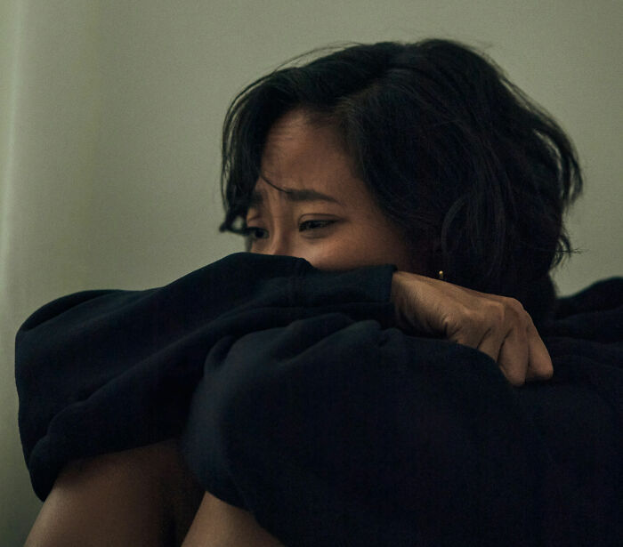 Woman sitting alone looking anxious and withdrawn, reflecting feelings related to postpartum OCD experiences.