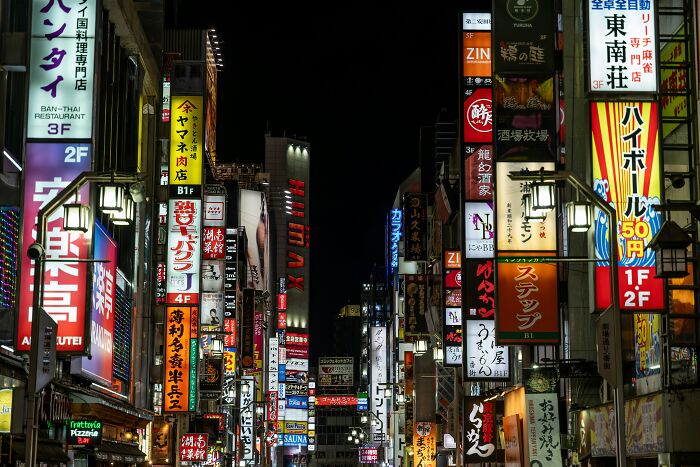 Busy Tokyo street at night with bright neon signs showcasing the reality of being big in Japan for foreigners.