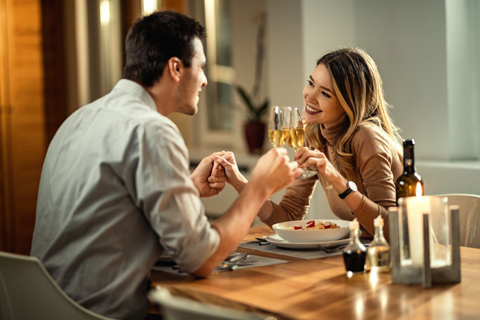 Couple holding hands over dinner table on first date, woman expressing no spark while man reacts demanding meal payment. Couple holding hands over dinner table on first date, woman expressing no spark while man reacts demanding meal payment.