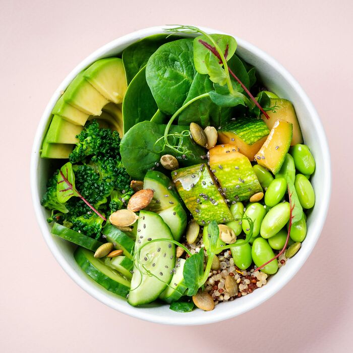 Healthy green salad bowl with spinach, avocado, broccoli, cucumber, and seeds promoting tobacco-free lifestyle.