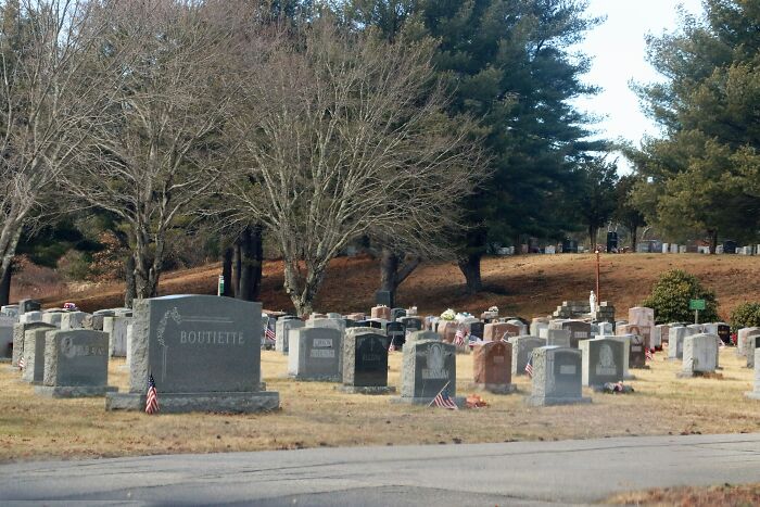 Cemetery with headstones and American flags in a peaceful setting, illustrating cultural practices that may shock Americans.