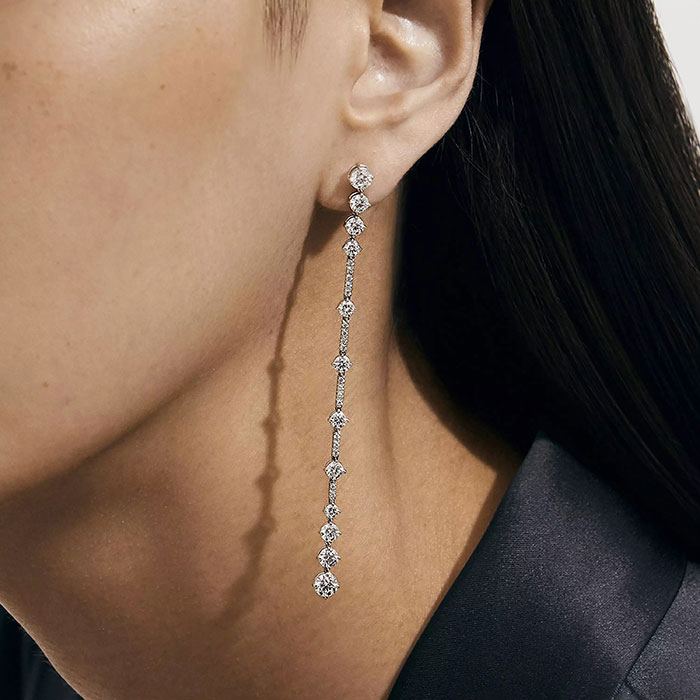 Close-up of a person's ear wearing a long diamond earring reflecting wealth display during Eras Tour outing. Close-up of a person's ear wearing a long diamond earring reflecting wealth display during Eras Tour outing.