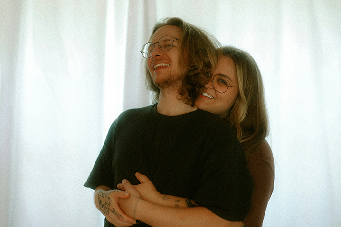 Young couple embracing indoors, man appearing concerned while seeking legal advice about potential lawsuit from girlfriend's mom.