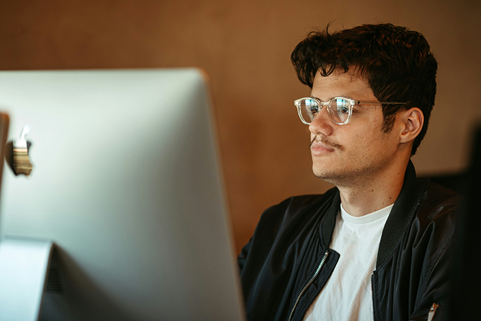 Man concerned about potential lawsuit and legal advice, sitting focused in front of a desktop computer.