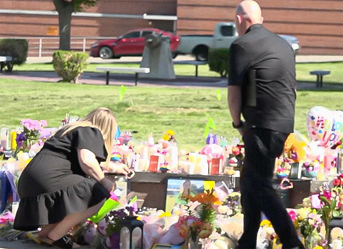 People paying respects at a memorial filled with flowers and candles where blood not belonging to a human was found.