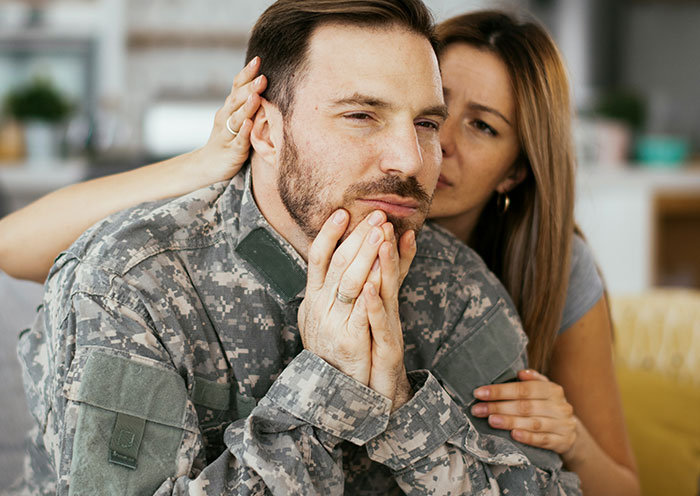 Man in military uniform looking worried while woman comforts him, illustrating delivery room stories about paternity uncertainty.