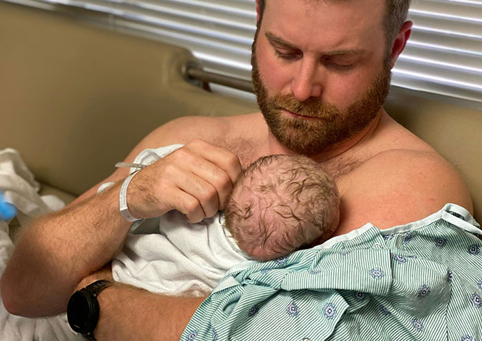 A man holding a newborn baby in a delivery room, capturing moments when the child is clearly not the father’s.