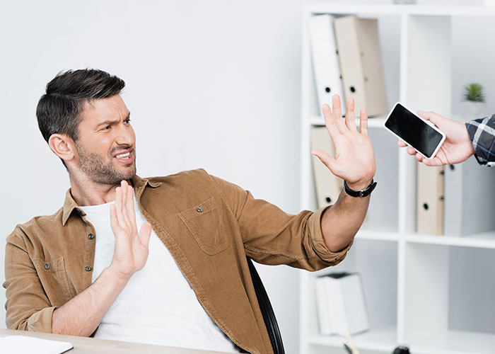 Man rejecting phone offered by friend, illustrating influencer-like dating preference and reality check conversation. Man rejecting phone offered by friend, illustrating influencer-like dating preference and reality check conversation.