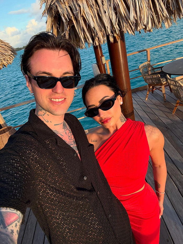 Demi Lovato and partner wearing sunglasses posing at a tropical waterfront location during honeymoon getaway. Demi Lovato and partner wearing sunglasses posing at a tropical waterfront location during honeymoon getaway.