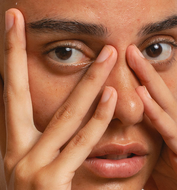 Close-up of woman touching her face, expressing concern about refusing to risk health for sister&rsquo;s wedding photo aesthetic.