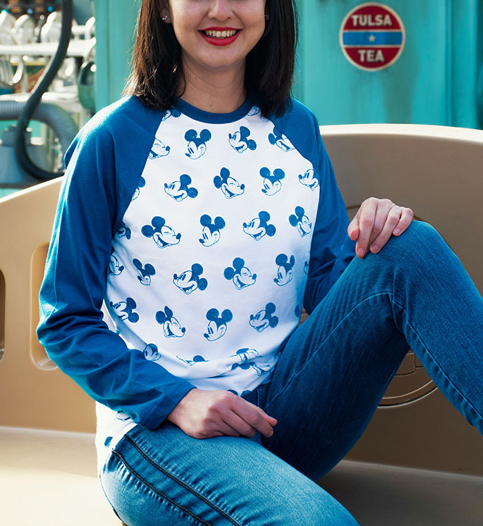 Woman wearing Disney-themed shirt sitting and smiling, related to Disney staff complaint about inappropriate outfit debate. Woman wearing Disney-themed shirt sitting and smiling, related to Disney staff complaint about inappropriate outfit debate.