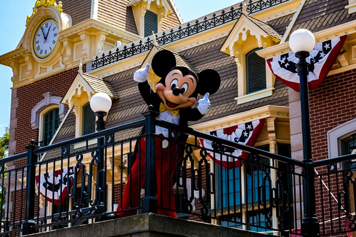 Mickey Mouse posing on balcony at Disneyland with guests, highlighting the $1K breakfast bill shock and dad’s reaction. Mickey Mouse posing on balcony at Disneyland with guests, highlighting the $1K breakfast bill shock and dad’s reaction.