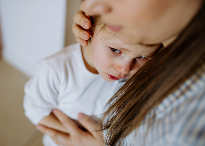 Young child with skin irritation being comforted by an adult, illustrating a bizarre medical case involving her skin.