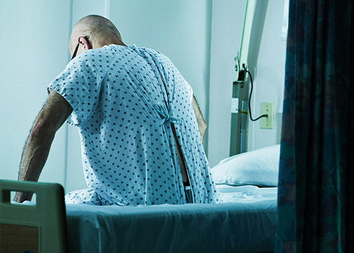Patient in hospital gown sitting on a bed, highlighting medical conditions that surprised doctors in a clinical setting.