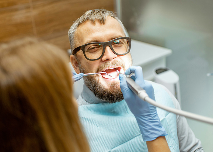 Man with glasses receiving dental treatment from healthcare professional highlighting medical conditions that surprised doctors.