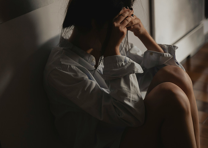 Woman sitting on the floor in distress, holding her head, representing unexpected medical conditions that surprised doctors.