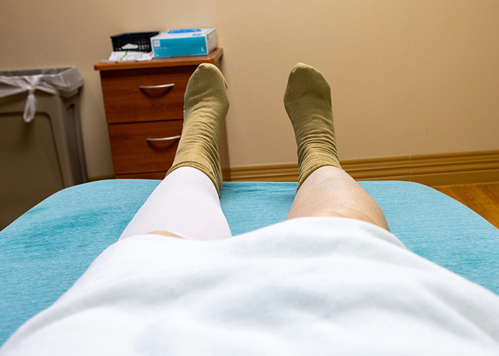 Patient lying on medical bed with compression sock on one leg, highlighting medical conditions that surprised doctors.