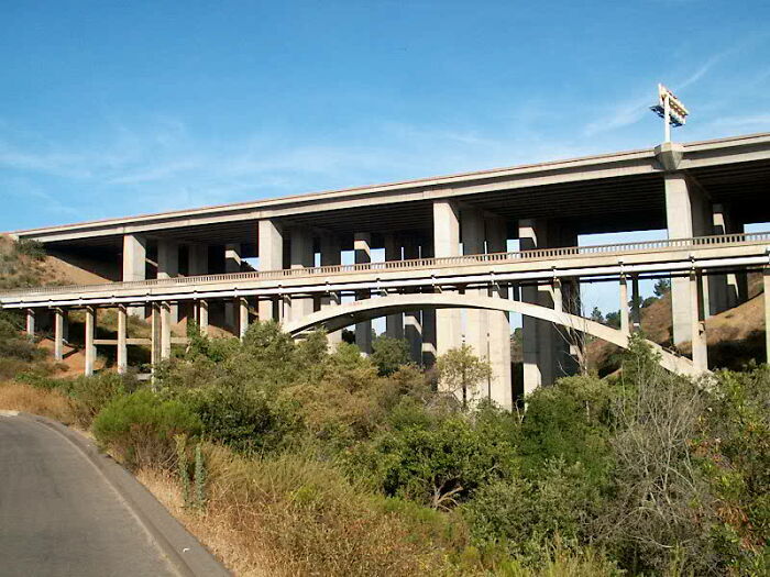 Empty highway bridge overgrown with vegetation under a clear blue sky, illustrating unsettling Wikipedia articles.