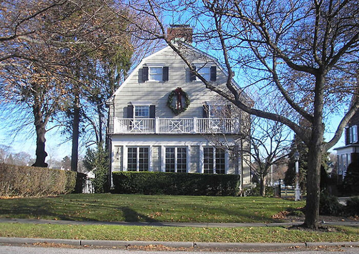 Old white house with bare trees under clear sky, evoking unsettling feelings linked to scary Wikipedia articles.