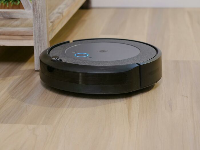 Robot vacuum cleaning on wooden floor near furniture, illustrating creative freedom in kids' art projects.
