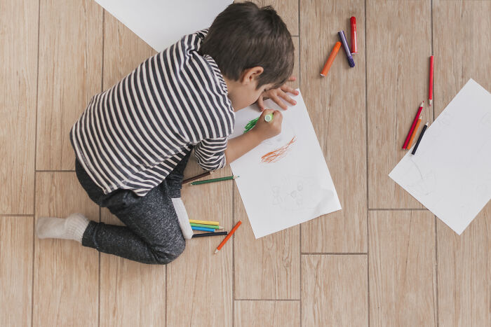 Young boy drawing on paper with colored markers, showcasing kids creative freedom in art activities at home.