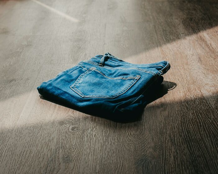 Folded blue jeans on wooden floor with natural light, symbolizing women over 42 embracing change and refusal to tolerate.