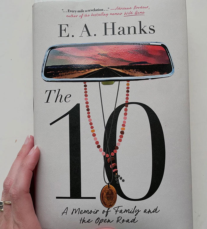 Book cover showing a memoir titled The 10 by E. A. Hanks with a rearview mirror reflecting a sunset road scene.