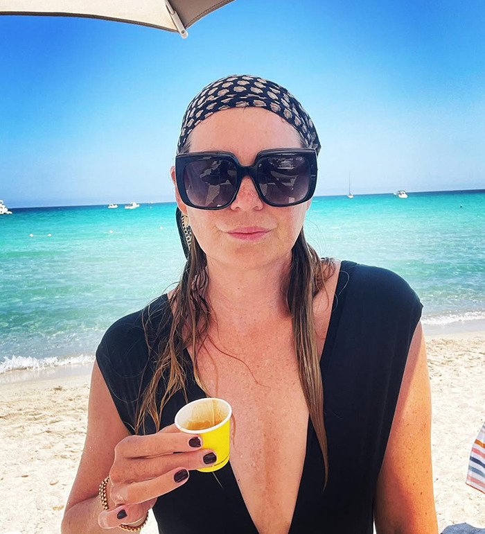 Woman wearing large sunglasses and a headscarf at the beach, representing Ellen Pompeo detained by TSA and explosives squad.