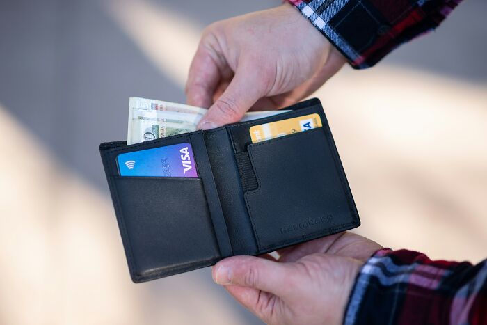 Person holding an open wallet with cash and credit cards, illustrating the shortcomings of being big in Japan.