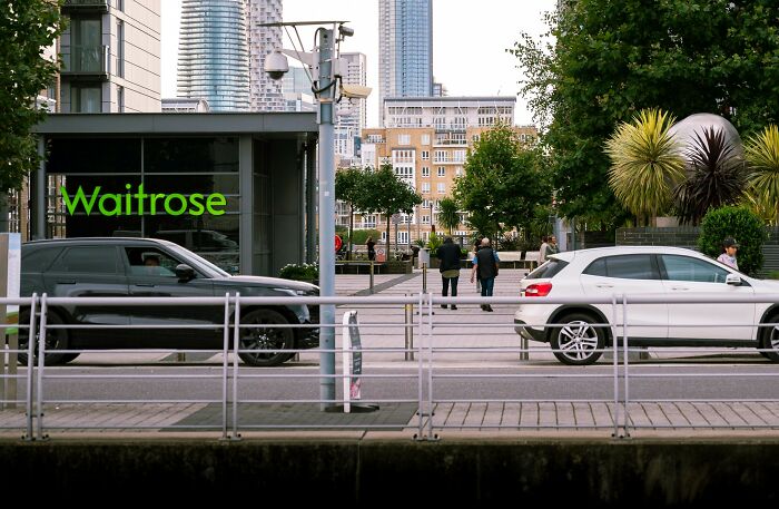Waitrose store with pedestrians and cars nearby in an urban setting, illustrating middle class lifestyle flags.