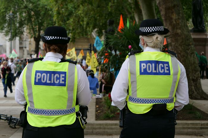 Two UK police officers in high-visibility vests monitoring a public gathering, reflecting views on the UK.