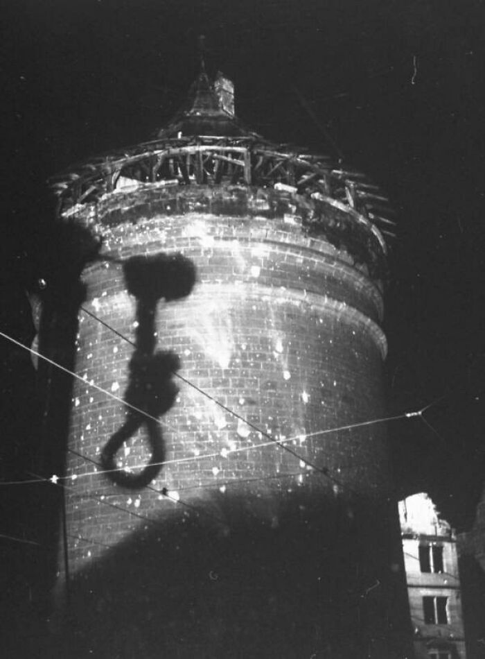 Shadow of a noose cast on an old stone tower, creating a creepy and unsettling atmosphere in this black and white photo.