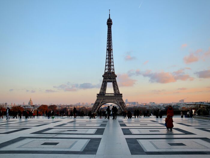 Eiffel Tower at sunset with tourists in Paris, representing European netizens correcting country misconceptions.