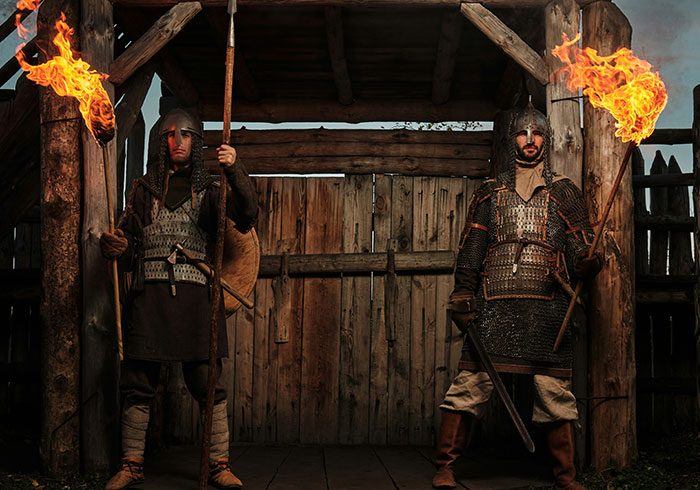 Medieval guards in armor holding torches at a wooden gate illustrating historical facts deemed common knowledge but incorrect.