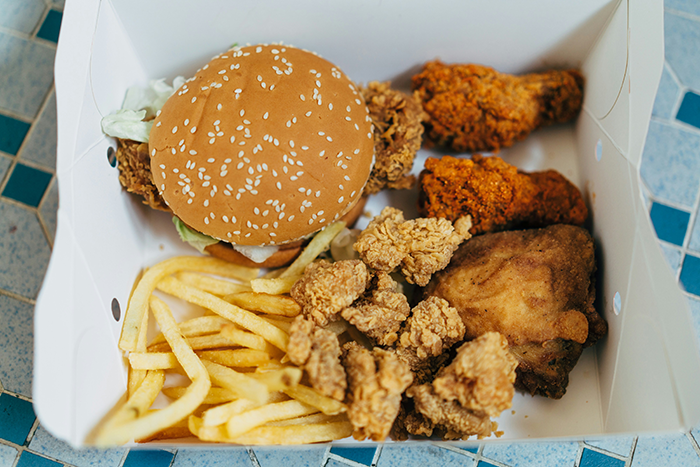 Fast-food wrappers and greasy fried chicken in a box disrupting an elegant wedding planned by the bride.