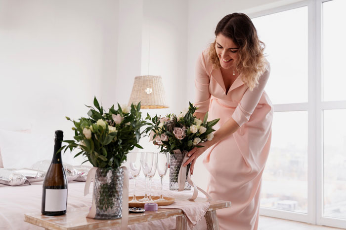 Woman arranging flowers on a table, representing mother of ring bearer shocked about being left off guest list despite help and RSVP.