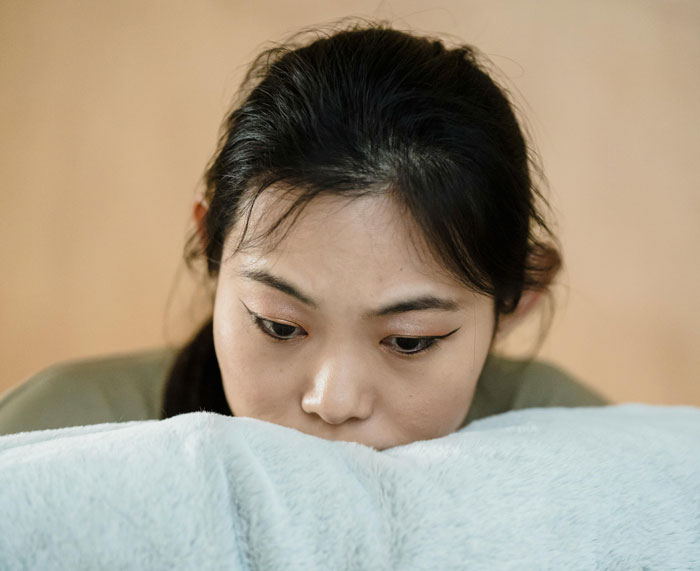 Mother of ring bearer looking shocked and upset, sitting alone with a worried expression indoors.