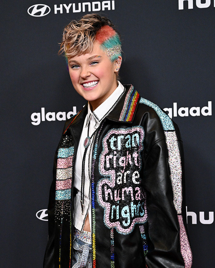 Person with colorful short hair wearing a sequined jacket at an event, related to famous lesbians boyfriend trend discussion.