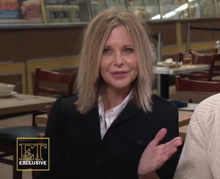 A woman speaking in an interview setting, highlighting Hollywood hypocrisy about women aging versus men aging like fine wine.