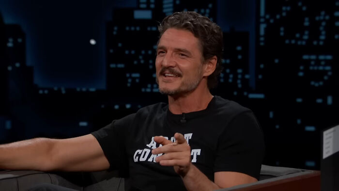 Actor in a black shirt smiling during a late-night Hollywood talk show discussing aging and hypocrisy.