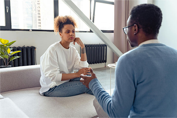 Young couple in serious conversation at home, reflecting the conflict of skipping wife&rsquo;s first Mother&rsquo;s Day for his mom.